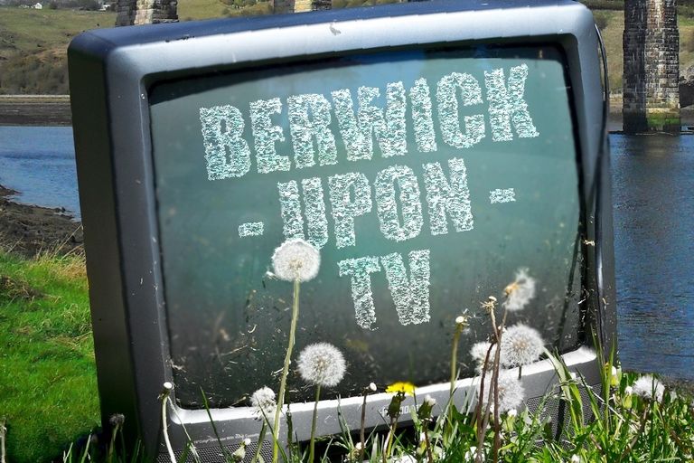 Promotional Image for Berwick Upon TV. A box tv sits in the grass with a backdrop of Berwick-upon-Tweed. The TV reads Berwick-upon-TV